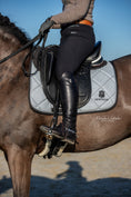Load image into Gallery viewer, Southlake Paws Royal Silver Saddle Pad on a horse, featuring a rider in black riding gear and tall boots.