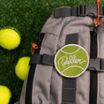 Load image into Gallery viewer, Southlake Paws Baller Patch backpack in gray with green logo, surrounded by tennis balls on a grassy surface.