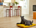 Load image into Gallery viewer, Cozy mat in chartreuse color with a dog resting on it, set in a modern kitchen with wooden flooring and bar stools.