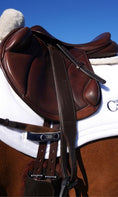 Load image into Gallery viewer, Southlake Paws Stable Ride Stirrup Leathers attached to a brown saddle on a horse, set against a clear blue sky.