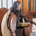 Load image into Gallery viewer, Sally Batton Pommel Blocker by Southlake Paws, featuring a brown leather design attached to a saddle.