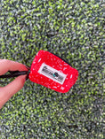 Load image into Gallery viewer, Red paisley poop bag holder from The Modern Dog Company, held in hand against a green grass background.
