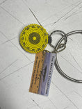Load image into Gallery viewer, Yellow beaded keychain with a circular design, attached to a metal keyring, featuring a tag that reads "The Kenyan Collection