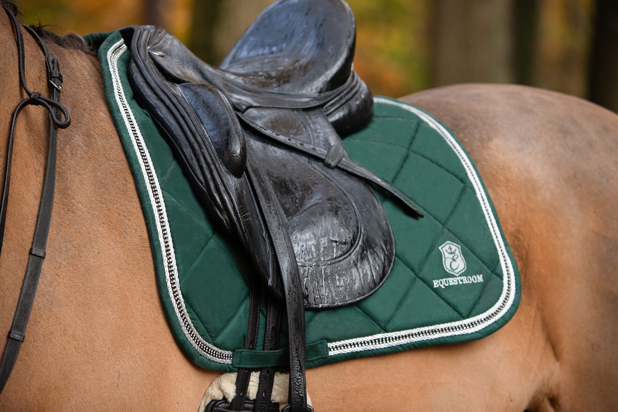 Southlake Paws Pine Grove Saddle Pad in green, placed under a black saddle on a horse, with a quilted design and logo.