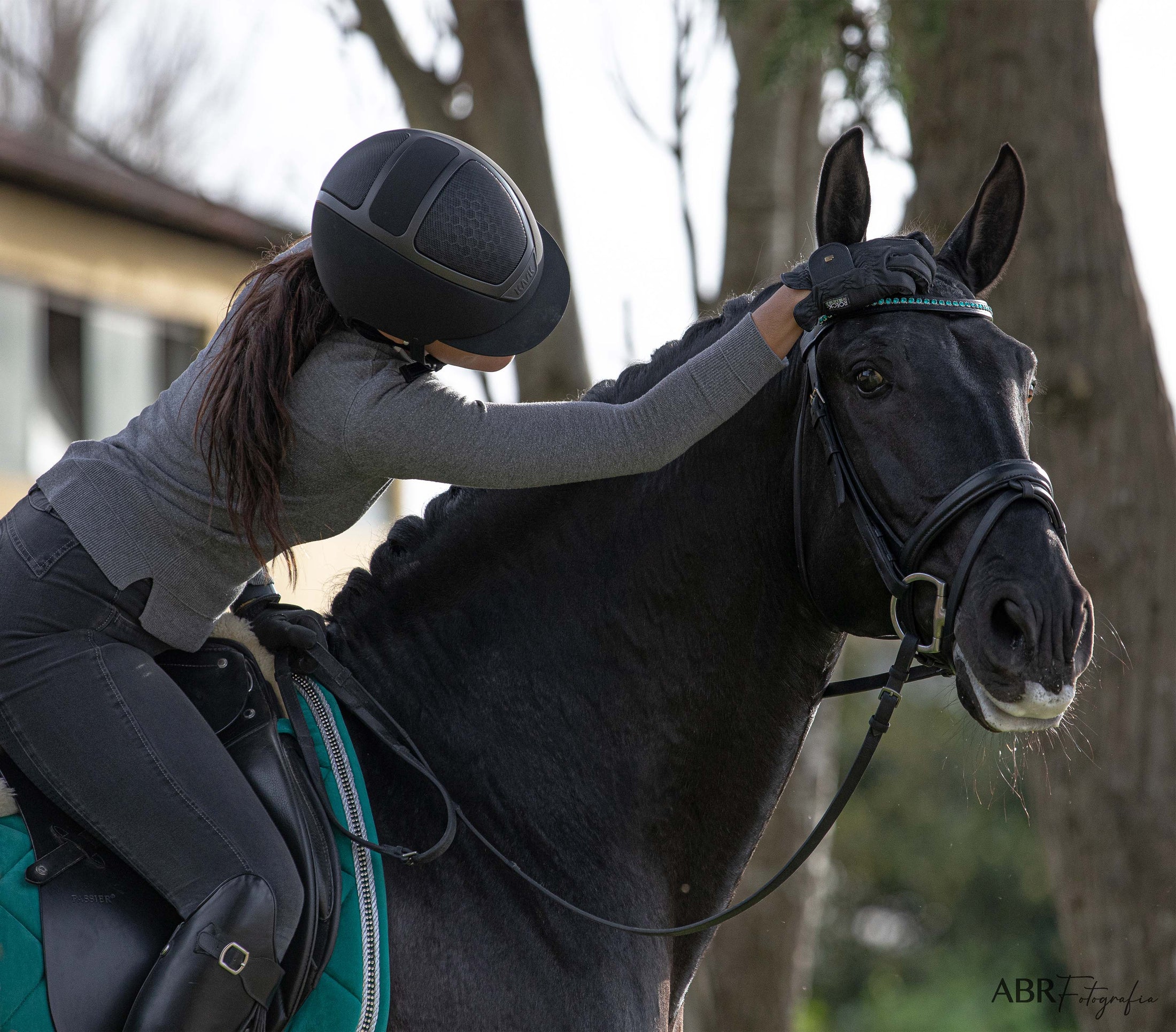 Teal Browband by Southlake Paws on a horse, rider in a helmet gently petting the horse's neck, outdoor setting.
