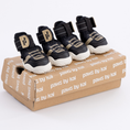 Load image into Gallery viewer, Four black and white pet boots on a branded cardboard box with 'paws by kai' text.
