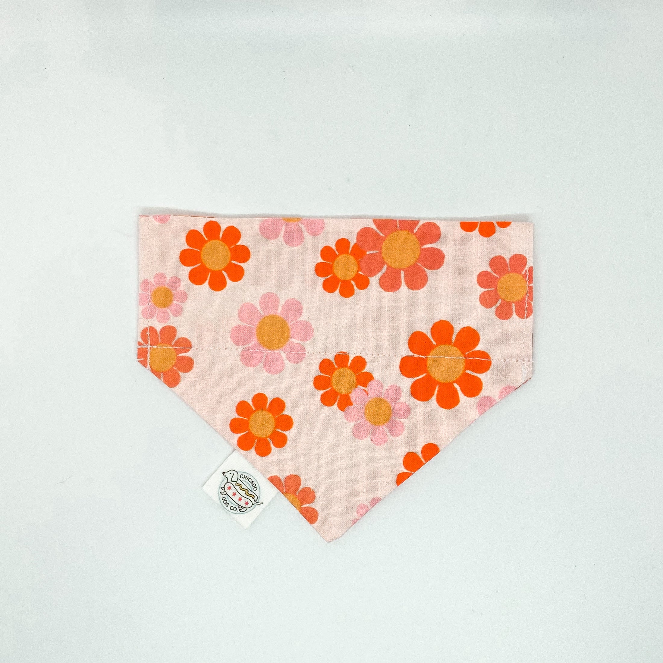 Flower Power Daisy Bandana by Southlake Paws featuring a pink background with colorful floral patterns in orange and yellow.