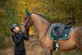 Load image into Gallery viewer, Southlake Paws Pine Grove Saddle Pad on a horse, with a rider in a helmet interacting affectionately with the horse in a natu
