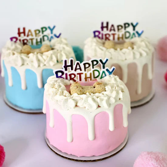 Three small birthday cakes with 'Happy Birthday' toppers on a white background