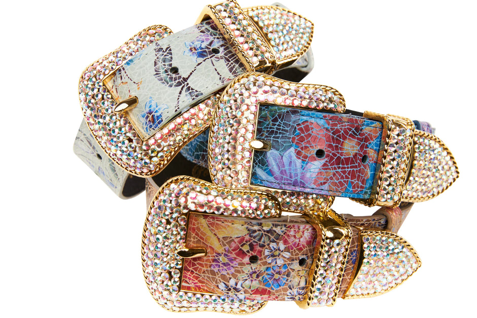 Decorative belt buckles with floral patterns and gold accents on a white background