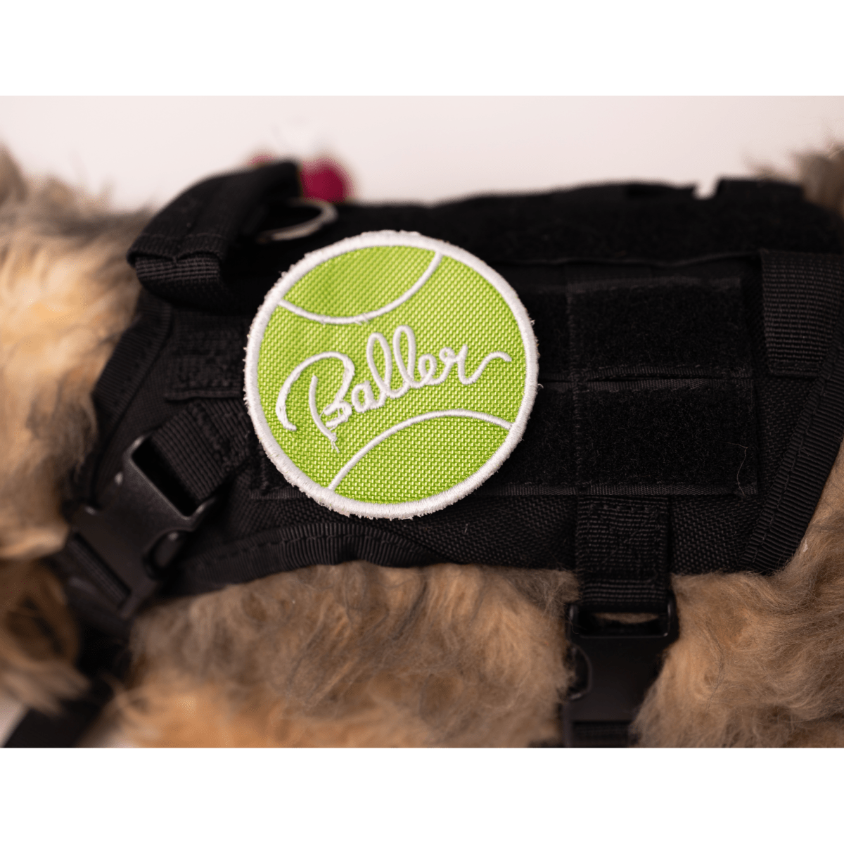 Green tennis ball patch with "Baller" text, attached to a black pet harness by Southlake Paws.