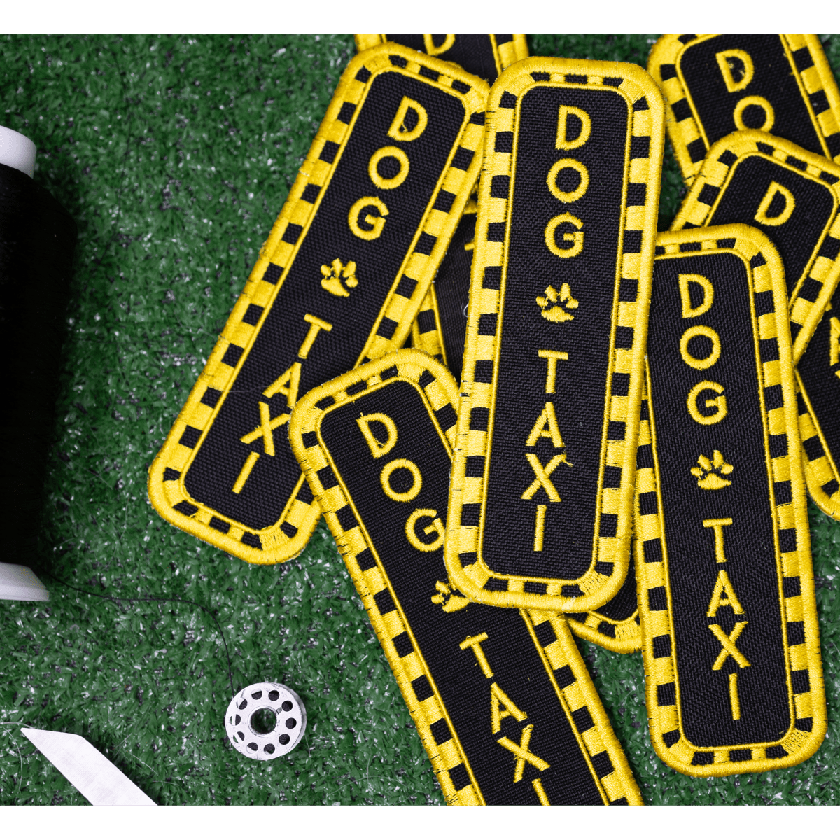 Southlake Paws Dog Taxi Patch featuring a black background with yellow text and accents, arranged on a green surface.