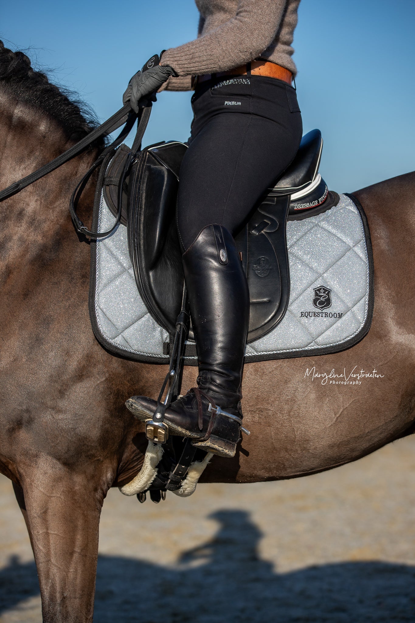 Southlake Paws Royal Silver Saddle Pad on a horse, featuring a rider in black riding gear and tall boots.