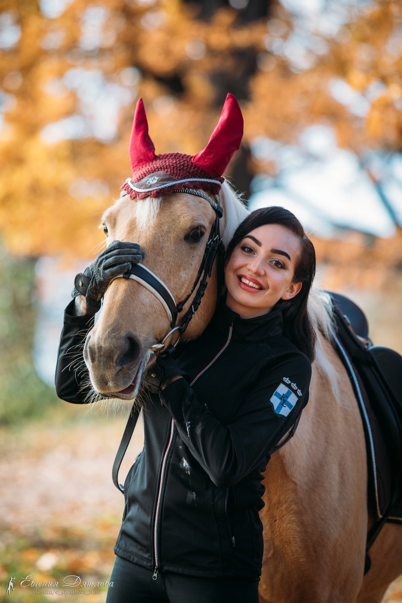 Burgundy Fly Hat by Southlake Paws, worn on a horse, with a rider smiling beside it in an autumn setting.