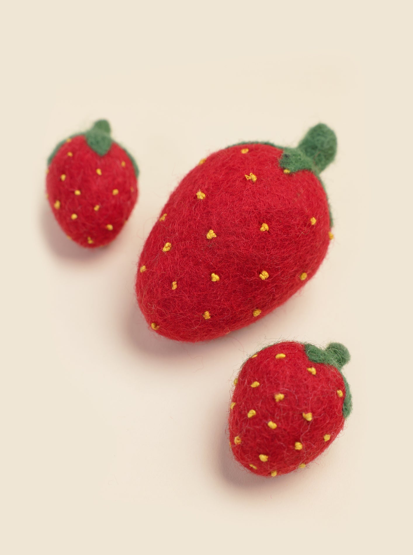Southlake Paws DOGGY STRAWBERRY: Three red felted strawberry toys with green leaves and yellow seeds, varying in size.