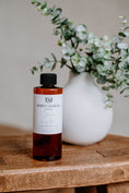 Load image into Gallery viewer, Luxury Electric Diffuser 8 OZ Refill by Southlake Paws, featuring a sleek bottle on a wooden surface with greenery in the bac
