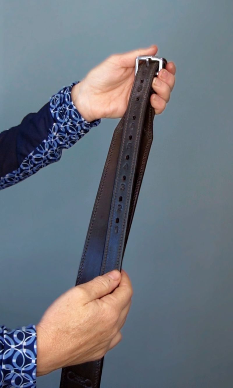 Stable Ride Stirrup Leathers by Southlake Paws held in a hand, showcasing the leather texture and adjustable holes.