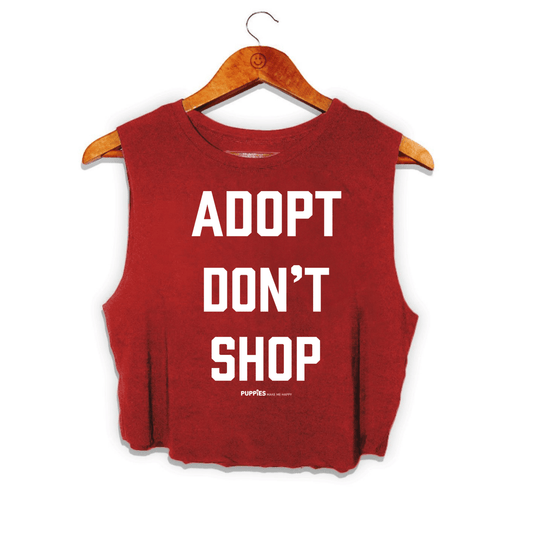 Red crop top with "ADOPT DON'T SHOP" printed in bold white letters, hanging on a wooden hanger. Ideal gift for dog lovers.