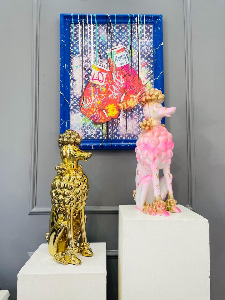Two decorative figurines on white plinths with a colorful abstract painting in the background.