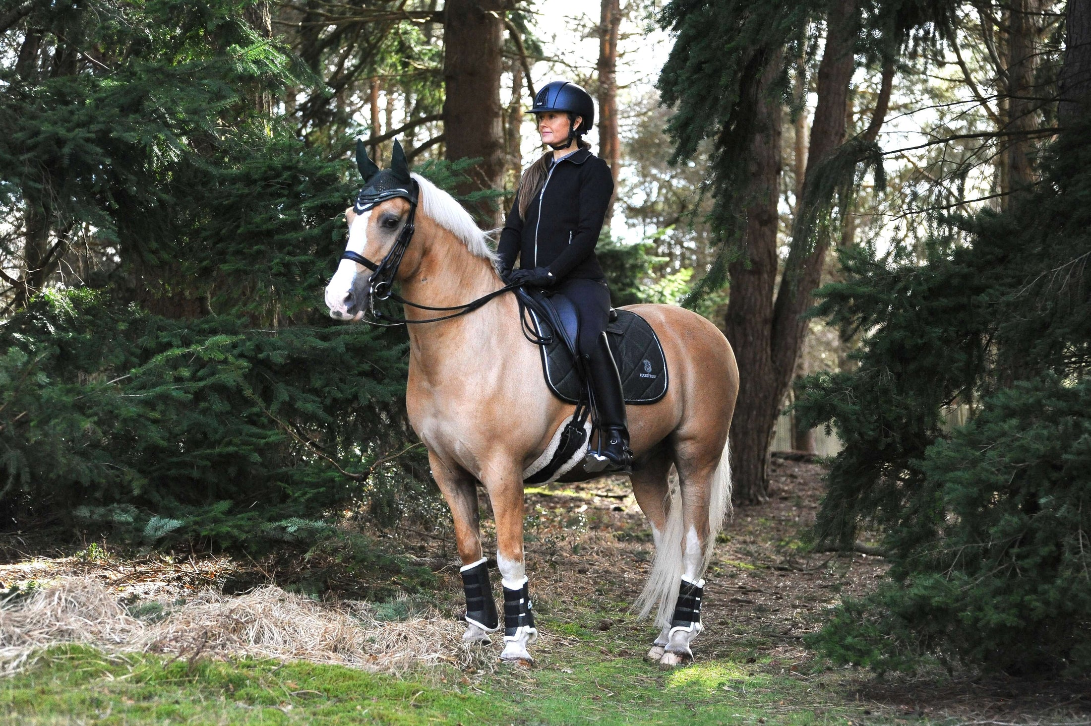 Southlake Paws Jade Green Boots worn by a rider on a horse in a forested area, surrounded by trees and greenery.