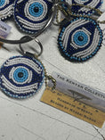 Load image into Gallery viewer, Colorful TKC Beaded Keychain by Southlake Paws, featuring an eye design with blue and white beads, attached to a keyring.
