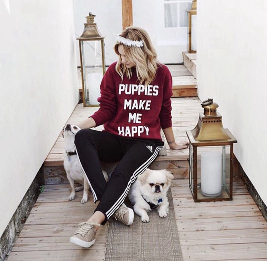 Maroon crewneck sweatshirt by Southlake Paws with "Puppies Make Me Happy" text, worn by a person sitting with two dogs.