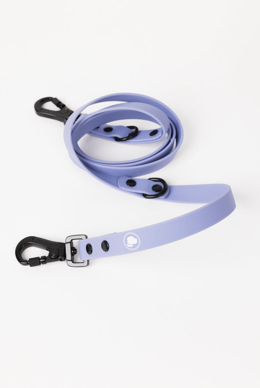 Lavender purple adjustable dog leash with black clips and buckle, featuring a logo on the strap. Ideal for pet owners.