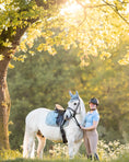 Load image into Gallery viewer, Southlake Paws Moonstone Blue Fly Hat worn by a rider next to a white horse in a sunlit outdoor setting.
