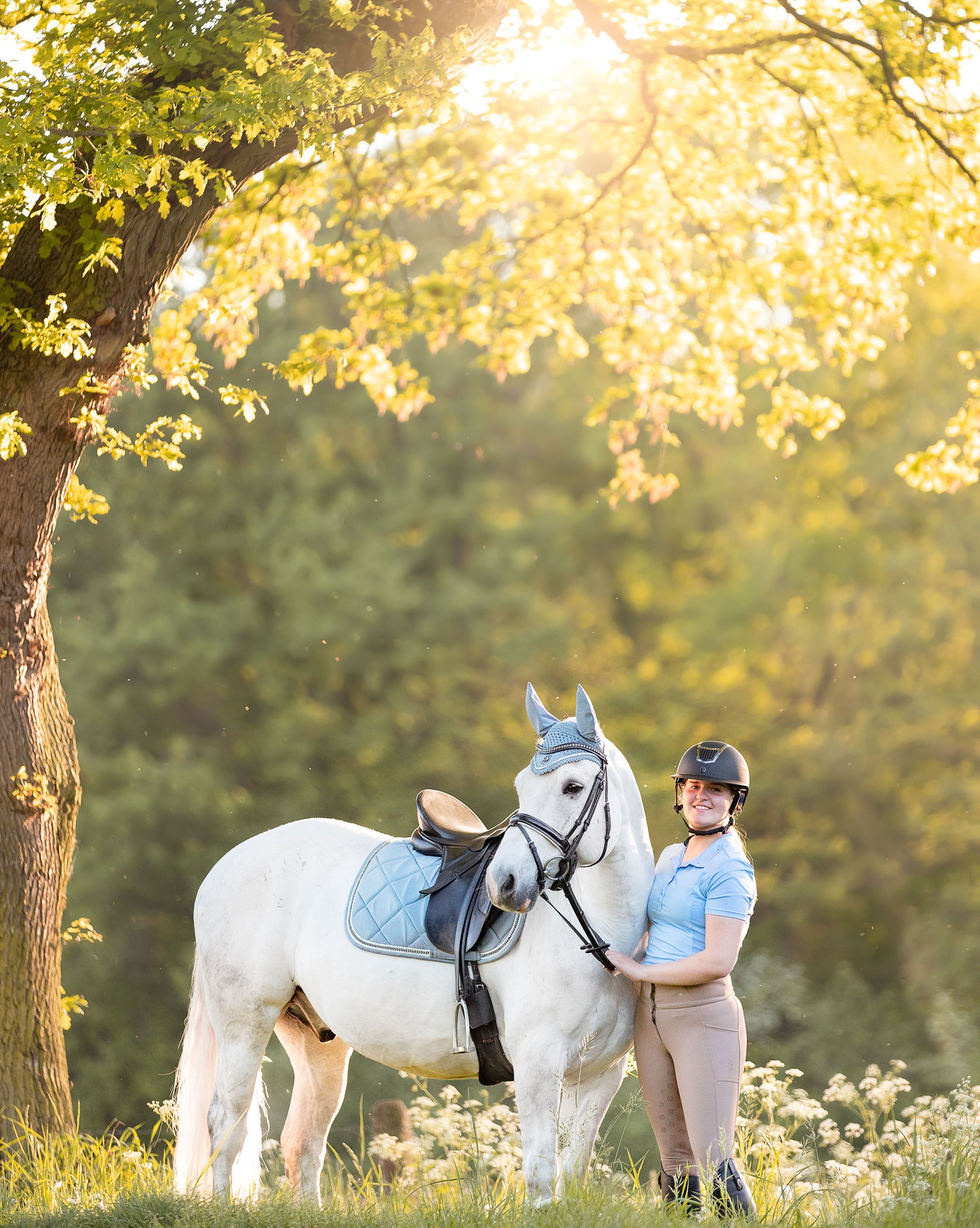 Southlake Paws Moonstone Blue Fly Hat worn by a rider next to a white horse in a sunlit outdoor setting.