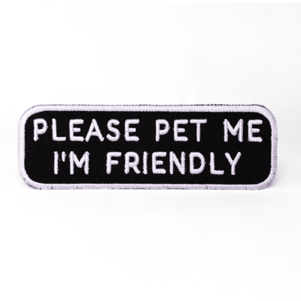 Black rectangular patch with white text reading "PLEASE PET ME I'M FRIENDLY" from Southlake Paws.